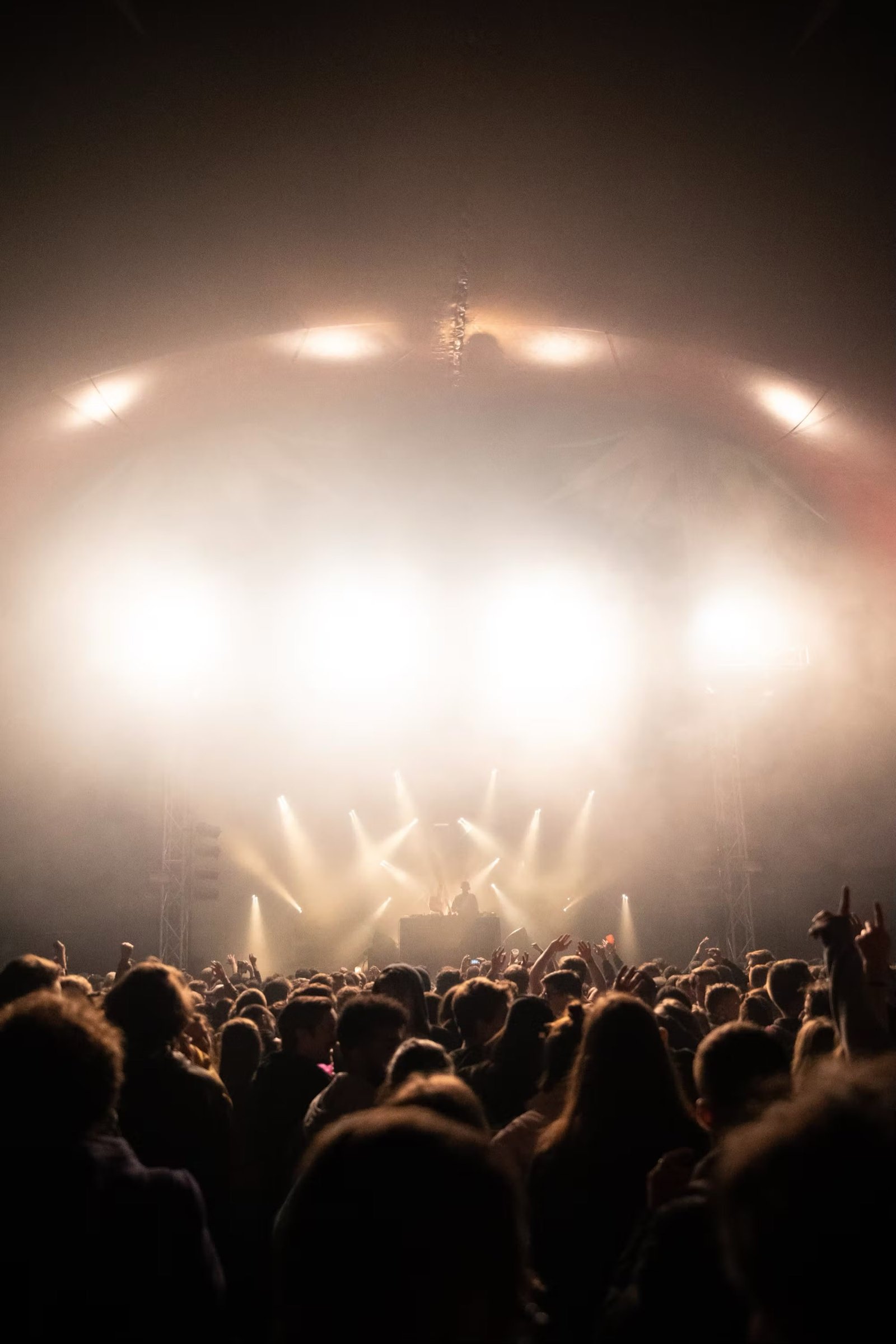 A festival stage washed in warm light over a full crowd.